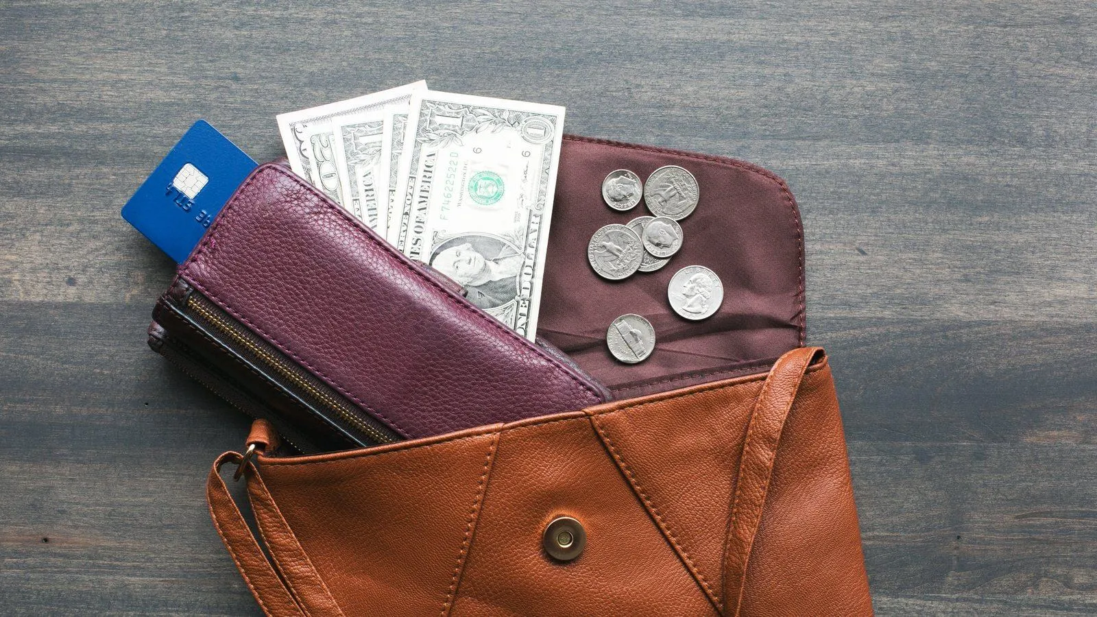 Uma carteira aberta sobre a mesa, com notas, moedas e um cartão saindo do bolso